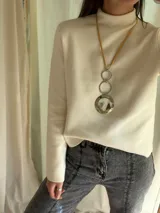 Collar largo con dije circular de guampa engarzado en alpaca plateada, aros de acero y tiento color ocre. Se cierra con cadena de acero quirúrgico con mosquetón para regular el largo.