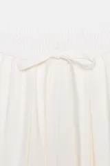 Pantalón fluido de tiro medio, color blanco, con cintura elástica ajustable con cordones, bolsillos laterales y bajo ajustable con trabilla y botón a presión.