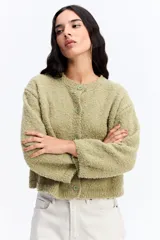 Saco de punto con textura tipo bouclé, de calce relajado y diseño levemente cropped. Cuenta con cuello redondo y cierre frontal mediante botones.