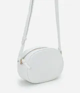 Cartera tipo camera bag de la marca Satinato, color blanco, con forma redondeada, superficie texturizada, correa ajustable, bolsillo delantero y cierre superior con cremallera dorada.