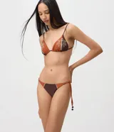 Bombacha de bikini con lazos laterales ajustables, confeccionada en microfibra bicolor marrón y terracota, con detalle de bordado de palmera y efecto levanta cola.