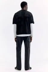 Pantalón cargo negro de nylon, de corte regular con cintura elástica ajustable con cordón. Cuenta con bolsillos laterales con cierre, bolsillos cargo con solapa en las piernas, bolsillos traseros con cierre y tensores en los tobillos.