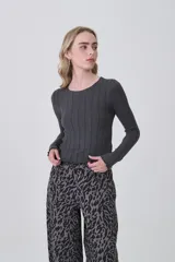 Remera de manga larga confeccionada en viscosa, con diseño entallado y cuello redondo a la base. Presenta una textura acanalada y terminaciones con ondas en los puños y el ruedo.