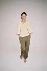 Jersey amplio de punto color beige, con escote redondo y mangas anchas por debajo del codo. Presenta detalles de calados en los laterales.