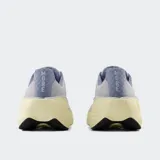 Championes de running New Balance modelo Fresh Foam More V5, color gris con detalles en lila y amarillo pálido. Presentan una entresuela Fresh Foam X sobredimensionada para máxima amortiguación, capellada de malla transpirable y ajuste mediante cordones.