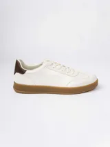 Championes urbanos de diseño minimalista en color blanco, con detalle de talón en color marrón oscuro y suela de goma color caramelo.