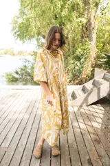 Vestido midi de corte camisero con estampado floral en tonos verde agua y crema. Presenta cuello a la base, cierre frontal con botones y mangas al codo con terminación elástica.