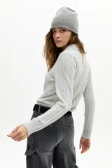 Sweater gris claro de punto con ochos, cuello polo y media cartera de botones. Confeccionado en algodón y cashmere.