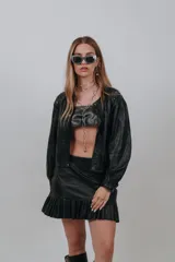 Minifalda negra de cuero sintético, de tiro alto y diseño ajustado, con un volado fruncido en el ruedo.