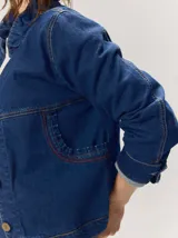 Campera de denim azul con cuello mao, cierre frontal con botones metálicos y presillas decorativas.