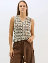 Chaleco de tejido crochet con diseño calado de motivos florales y geométricos. Presenta escote en V, cierre frontal con botones y detalles de vivos a contraste en color negro en sisas, escote y ruedo.