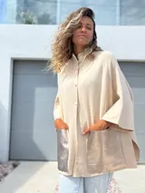 Saco tejido de punto en color crudo, con diseño holgado, mangas tres cuartos y bolsillos frontales grandes confeccionados en cuero metalizado plateado.