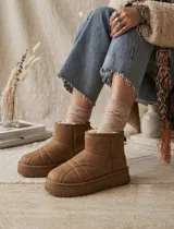 Pantubota de caña baja en color beige, con diseño acolchado de costuras curvas y plataforma dentada. Interior forrado en piel sintética para mayor calidez.