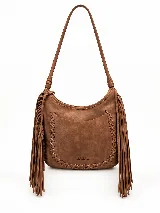 Cartera tipo hobo de cuero vacuno color tostado, con diseño amplio y flexible, decorada con un trenzado artesanal en el frente y largos flecos laterales. Cuenta con correa larga para llevar al hombro.
