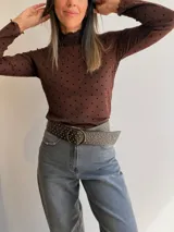 Remera de tul de manga larga con estampado de lunares negros sobre fondo blanco. Presenta cuello y bordes con terminación ondulada.