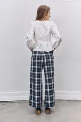 Pantalón sastrero de corte recto y tiro alto con estampado de cuadros escoceses en tonos azul marino, blanco y líneas finas en naranja. Presenta pinzas en la cintura y cierre frontal.