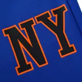 Pantalón de jogging azul de los New York Knicks, con cordón ajustable en la cintura, bolsillos y puños acanalados en color naranja. Presenta estampado lateral con la inscripción 'NY' y el logo de la NBA.
