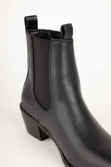 Bota de cuero color marrón con elástico negro en los laterales, caña baja, punta fina y taco cuadrado.