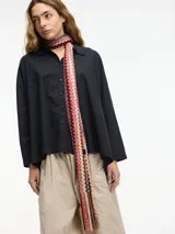 Camisa de corte oversize, color negro, con cuello camisero y cierre frontal de botones. Presenta mangas largas y un diseño holgado.