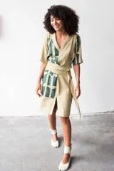 Vestido color beige con estampado abstracto en verde, confeccionado en lana, seda y algodón. Diseño cruzado con cuello en V texturizado y lazo lateral.