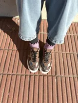 Zapatillas deportivas de cuero color peltre, con cordones negros y suela de goma blanca.