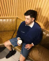 Buzo azul marino de corte clásico con cuello redondo, puños y cintura acanalados. Presenta un bolsillo cuadrado en el pecho y logo de la marca bordado en blanco.