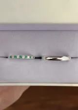 Set de dos anillos de plata 925. El primero es una alianza fina con engaste de zirconias blancas y piedras verdes alternadas. El segundo es una alianza lisa de diseño bombé.