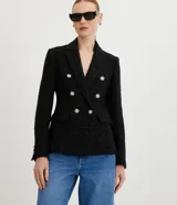 Blazer negro de tweed con hilos metalizados, corte entallado, escote en V profundo, bolsillos delanteros con solapa y doble botonadura con seis botones decorativos de strass.