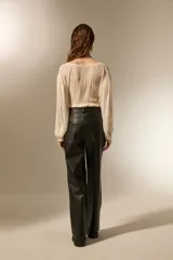 Pantalon de corte recto confeccionado en eco-cuero negro, con tiro medio y costuras horizontales a la altura de la rodilla.