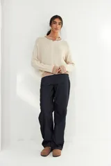 Bomber de tejido de punto color crudo, con cierre frontal completo y detalles de franjas multicolores en cuello, puños y ruedo.