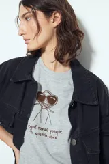 Remera blanca de manga corta con estampa frontal de un personaje con lentes de sol y la frase "Llegué tarde porque no quería venir". Tiene silueta relajada y calce cómodo, con un corte asimétrico en el bajo.