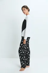 Pijama compuesto por una remera de manga larga blanca y un pantalón negro con estampado de corazones blancos. El pantalón cuenta con cintura elástica para mayor comodidad.