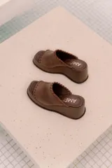 Sandalias de plataforma color marrón, con diseño de una sola tira ancha con detalle de costuras expuestas en los bordes y punta cuadrada.