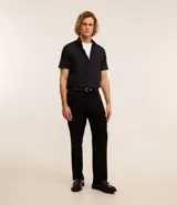 Camisa de manga corta con cuello inglés y cierre frontal abotonado, confeccionada en una mezcla de fibras de bambú, viscosa, poliéster y elastano. Presenta un diseño liso y entallado.