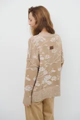 Buzo de tejido de punto con cuello redondo, mangas largas con puños acanalados y diseño estampado de flores en tonos rojos.