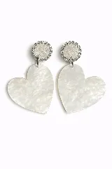 Aros colgantes con diseño de corazón en material acrílico efecto nácar, con base circular superior adornada con cristales brillantes.