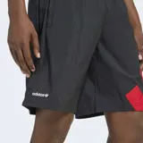 Short Adidas Adicolor Blocked de corte clásico, confeccionado en tejido plano de poliamida reciclada. Presenta un diseño en color negro con el icónico logo de las tres tiras en bloques de color rojo en el lateral. Cuenta con cintura elástica con cordón de ajuste.
