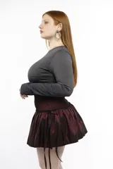 Minifalda negra de tafeta con cintura alta elastizada, diseño con volado y lazos laterales ajustables.