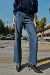 Jeans de tiro alto con diseño de cinco bolsillos, pernera recta y corte largo. Presenta cierre frontal con cremallera y botón metálico.