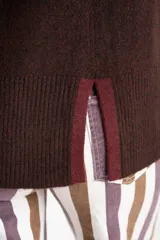 Polera de punto con calce oversize, cuello alto y mangas largas. Presenta un diseño en color negro con franjas laterales en las mangas y detalle en el cuello en tono bronce con acabado brillante.