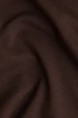 Remera de manga larga color marrón oscuro, con escote asimétrico que deja un hombro al descubierto. Presenta frunces laterales que generan un efecto drapeado en el torso.