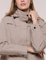 Campera impermeable Gallery de color beige, con capucha plegable, cierre frontal oculto con botones a presión, bolsillos delanteros y cordón de ajuste en la cintura.