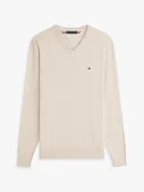 Sweater Tommy Hilfiger de cuello en V y manga larga, color beige, confeccionado en mezcla de algodón y poliéster. Presenta puños y bajo de punto canalé, con el logo de la marca bordado en el pecho.