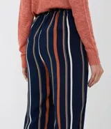 Pantalón de viscosa con rayas verticales en azul marino, blanco y naranja. Tiene bolsillos laterales, cintura elástica con cordón ajustable y tobillos ajustados con elástico.
