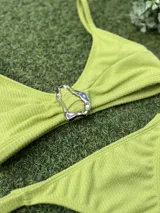 Conjunto de bikini color lima con textura, compuesto por un top triangular con detalle de hebilla metálica plateada en el centro y bombacha colaless.