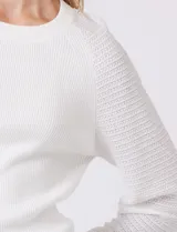 Buzo de punto marca Zac & Rachel en color blanco, con cuerpo de textura acanalada y mangas largas con diseño de punto calado. Presenta cuello redondo a la base y puños ajustados.
