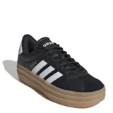 Championes urbanos Adidas modelo VL Court Bold, color negro con las icónicas tres rayas laterales en blanco y suela de plataforma en tono caramelo. Presentan un diseño de corte bajo con cordones y detalles de marca en la lengüeta y el lateral.