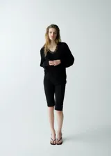 Jersey negro de punto de corte holgado, con cuello en V adornado con detalles de encaje y manga larga.