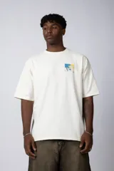 Remera de corte oversize confeccionada en algodón grueso de color crudo. Presenta un diseño minimalista con una pequeña estampa rectangular en el pecho que reinterpreta una obra impresionista con tonos azules y amarillos.