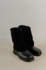 Botas de caña media color negro, con base de cuero texturado, puntera cuadrada y manga superior de gamuza. Cuentan con cierre lateral interno.